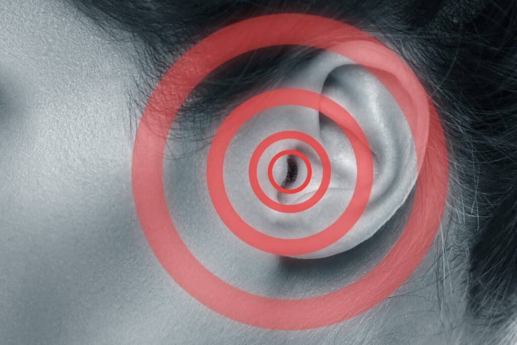 Gros plan sur l'oreille d'une personne avec des signaux rouges de vibrations.