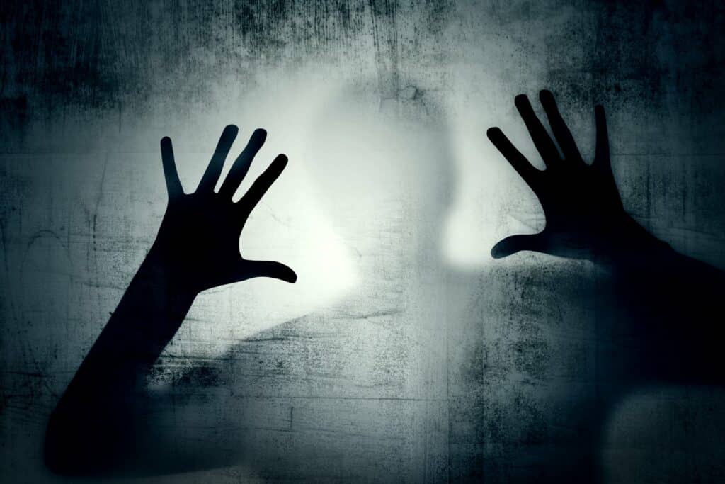image d'une ombre humaine qui pose ses mains sur une paroi