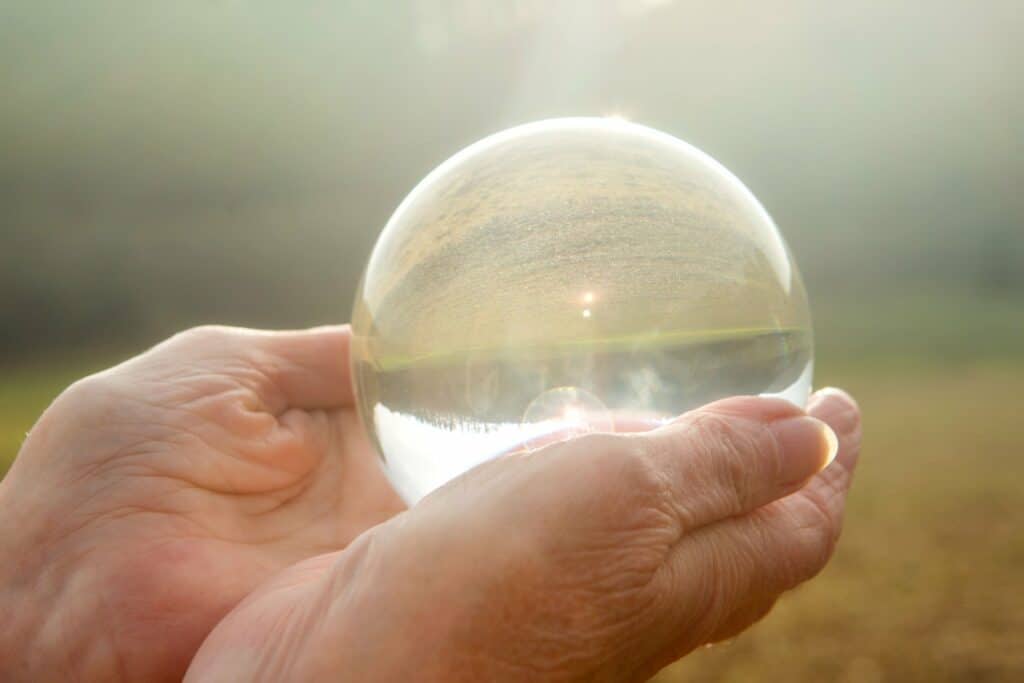 deux mains ridées tiennent une boule de cristal transparente