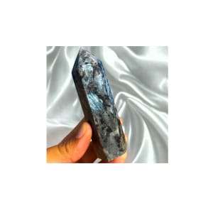 Plongez dans l'élégance sombre et mystérieuse de cette colonne de Larvikite de 10 cm, souvent surnommée « Pierre de Lune Noire » ou « Feldspath norvégien ».