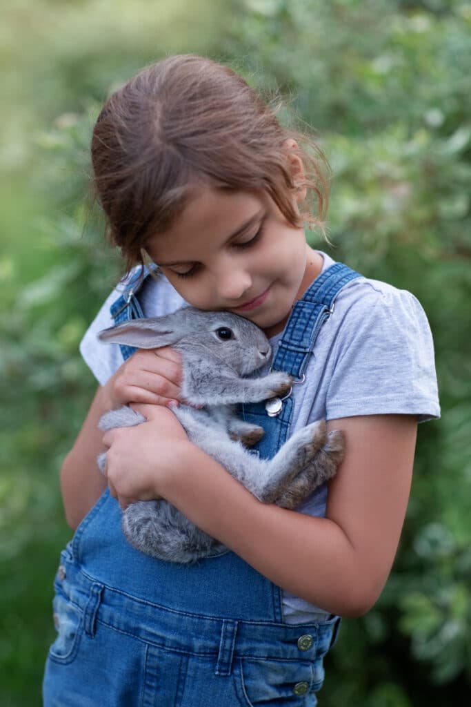 Une petite fille tenant un petit lapin dans ses bras.